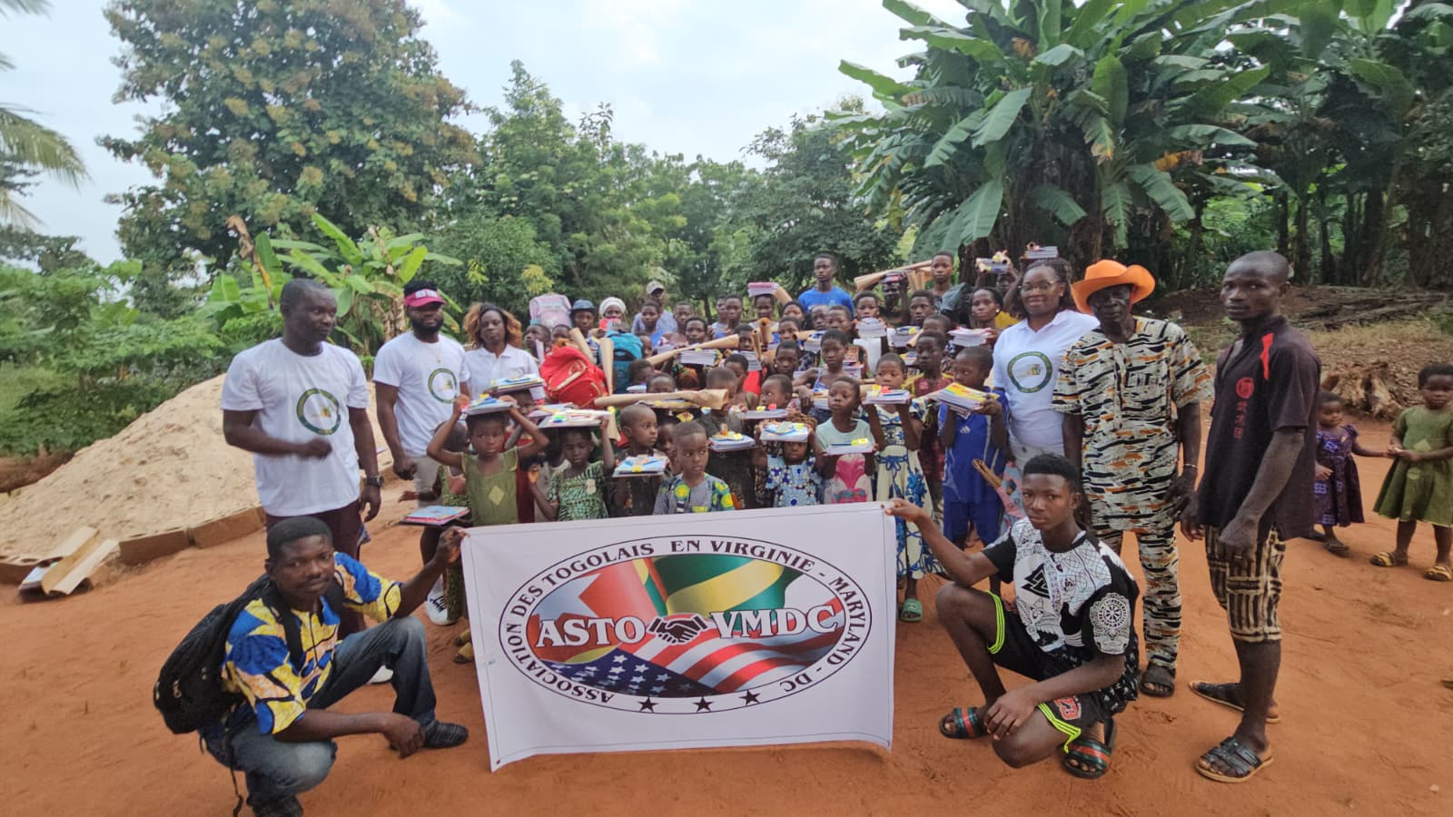 Volunteers and children gathered with the ASTO-VMDC banner during a supply distribution