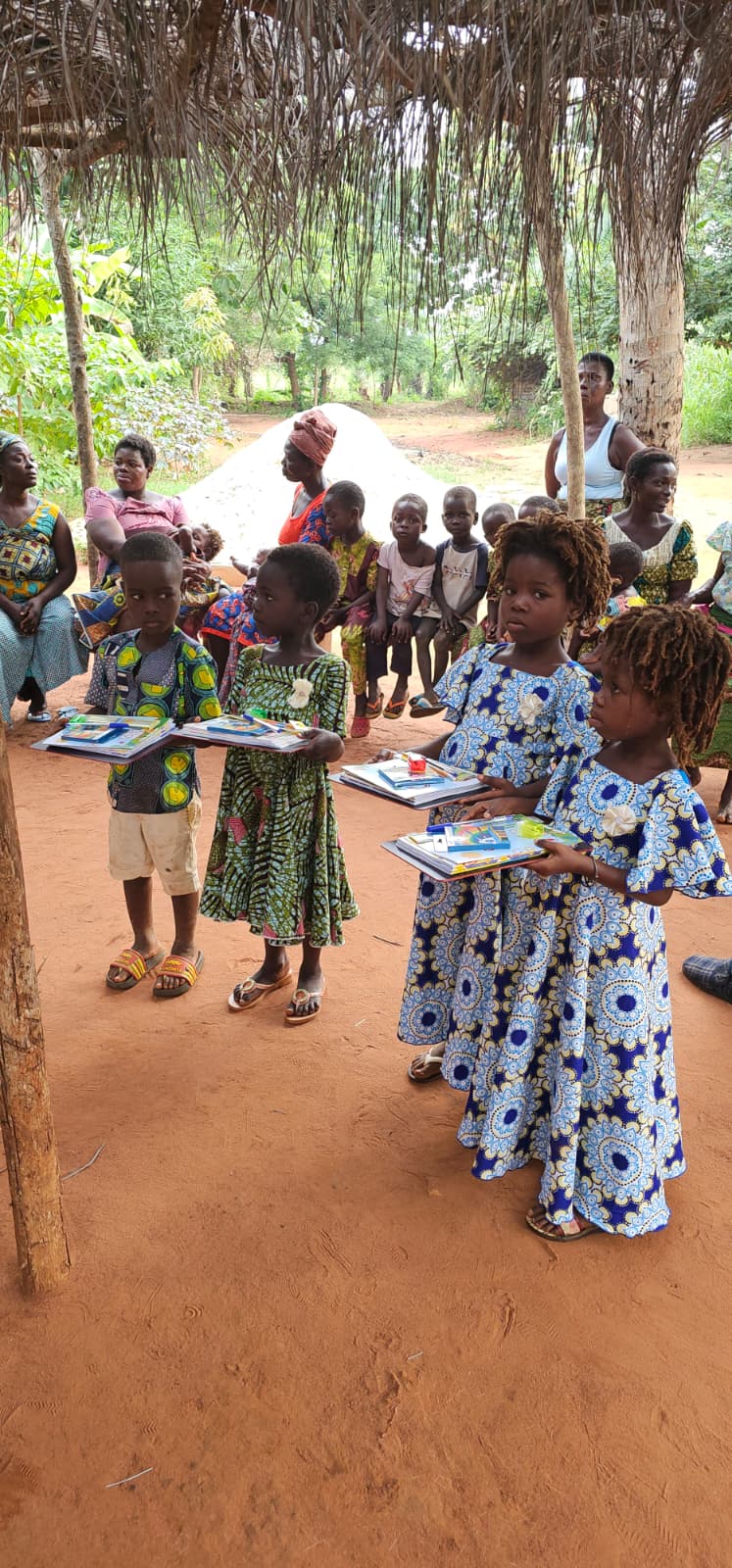 Children in colorful traditional dress holding new notebooks and school supplies